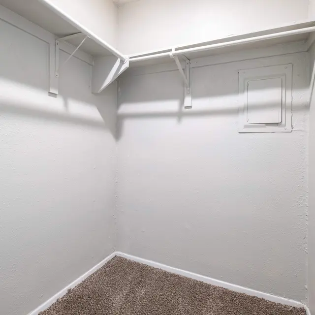 An empty closet with white walls and shelves.