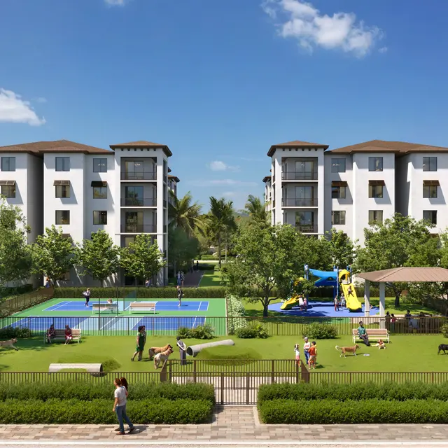 A modern residential complex featuring multiple white buildings with brown roofs surrounded by green lawns, trees, and recreational areas. In the foreground, there are playground equipment and tennis courts. People are engaging in leisure activities.