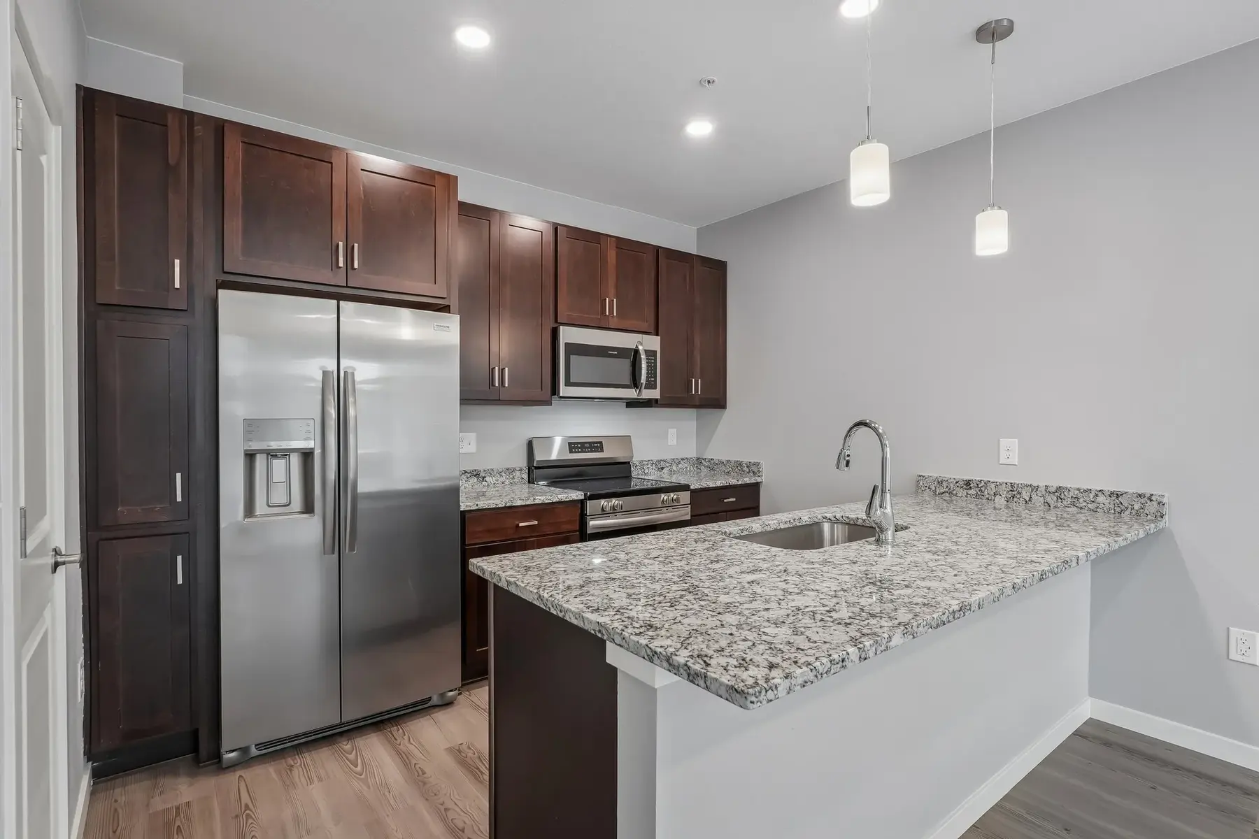 Modern Kitchen with Granite Countertop A modern kitchen featuring dark wood cabinets, stainless steel appliances, and a granite countertop with an island.