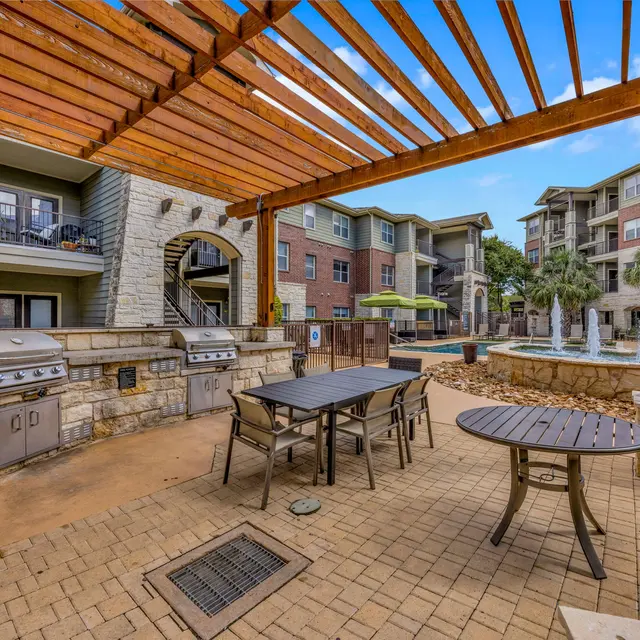 Outdoor grilling area with BBQ grills and seating in an apartment complex courtyard.