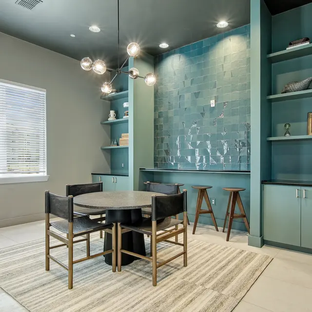 A modern dining space featuring a round table, stylish chairs, shelves, and a blue accent wall with decorative items.