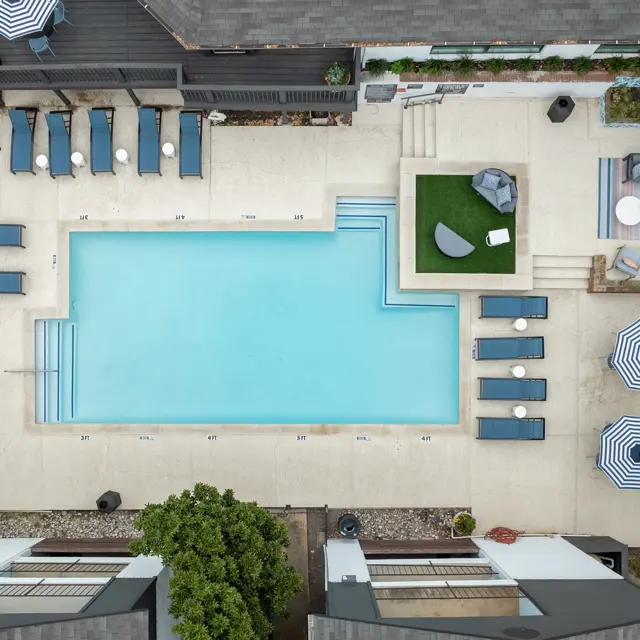 Aerial view of a modern outdoor pool area with lounge chairs and umbrellas.