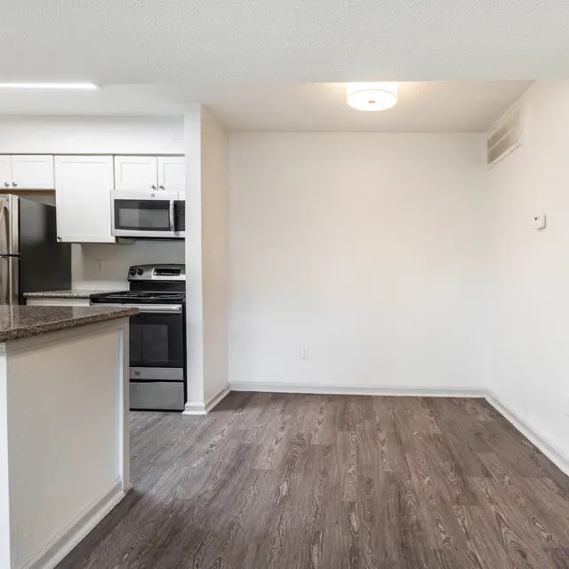 A modern kitchen with stainless steel appliances and an open floor plan leading into a spacious living area.