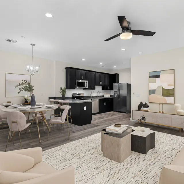 A modern and spacious living room with an open kitchen layout, featuring a light-colored sofa and stylish furniture.