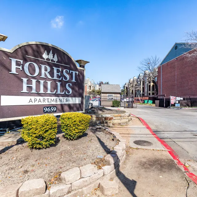 Sign for Forest Hills Apartments displayed prominently with manicured bushes in front.