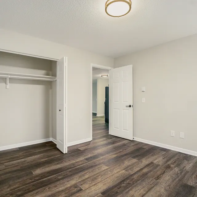Interior view of an empty bedroom featuring a closet and doorways to other rooms.