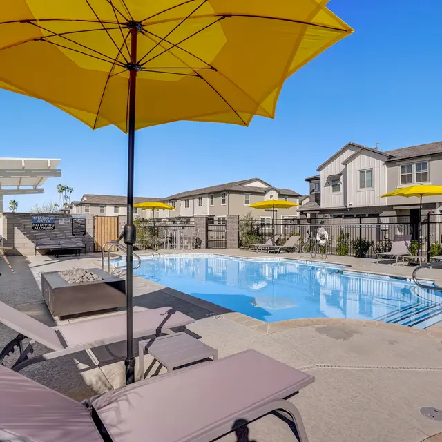 Sunny Poolside Retreat A bright, inviting swimming pool area featuring a clear blue pool surrounded by lounge chairs and umbrellas.
