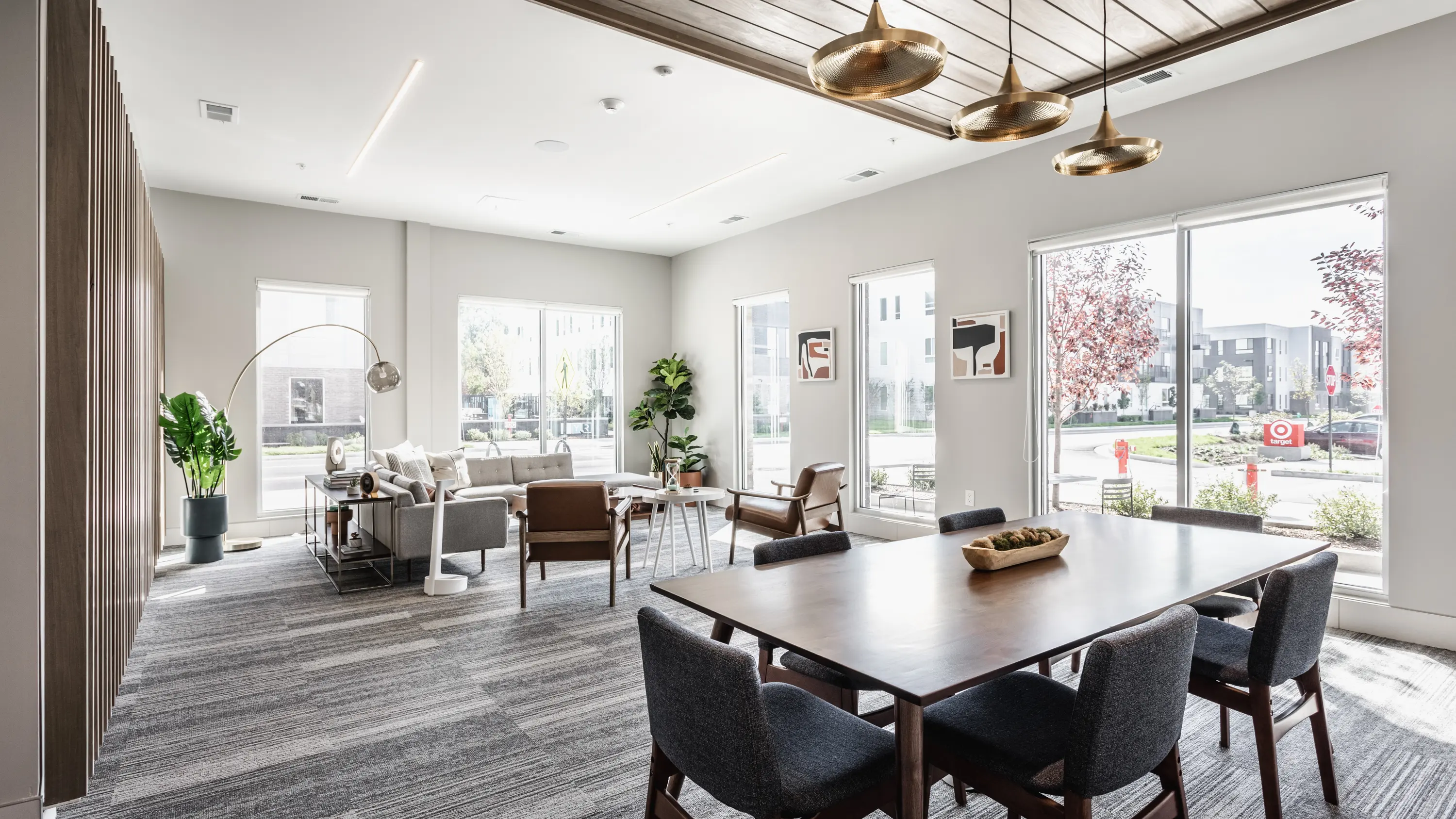 A modern living space with large windows, natural light, a cozy seating area, and a dining table.
