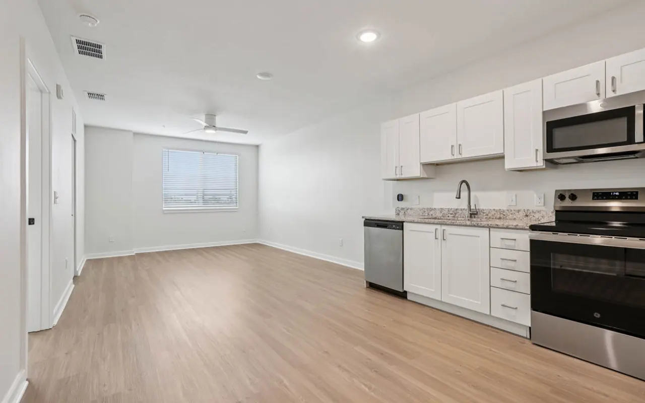 Modern Kitchen and Living Area A spacious modern kitchen and living area with white cabinets and stainless steel appliances. The room has large windows allowing natural light.