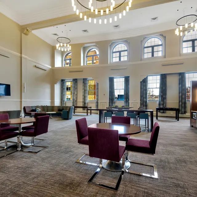 Spacious Modern Lounge Area Spacious lounge area featuring purple upholstered chairs and circular wooden tables, with large windows allowing natural light.