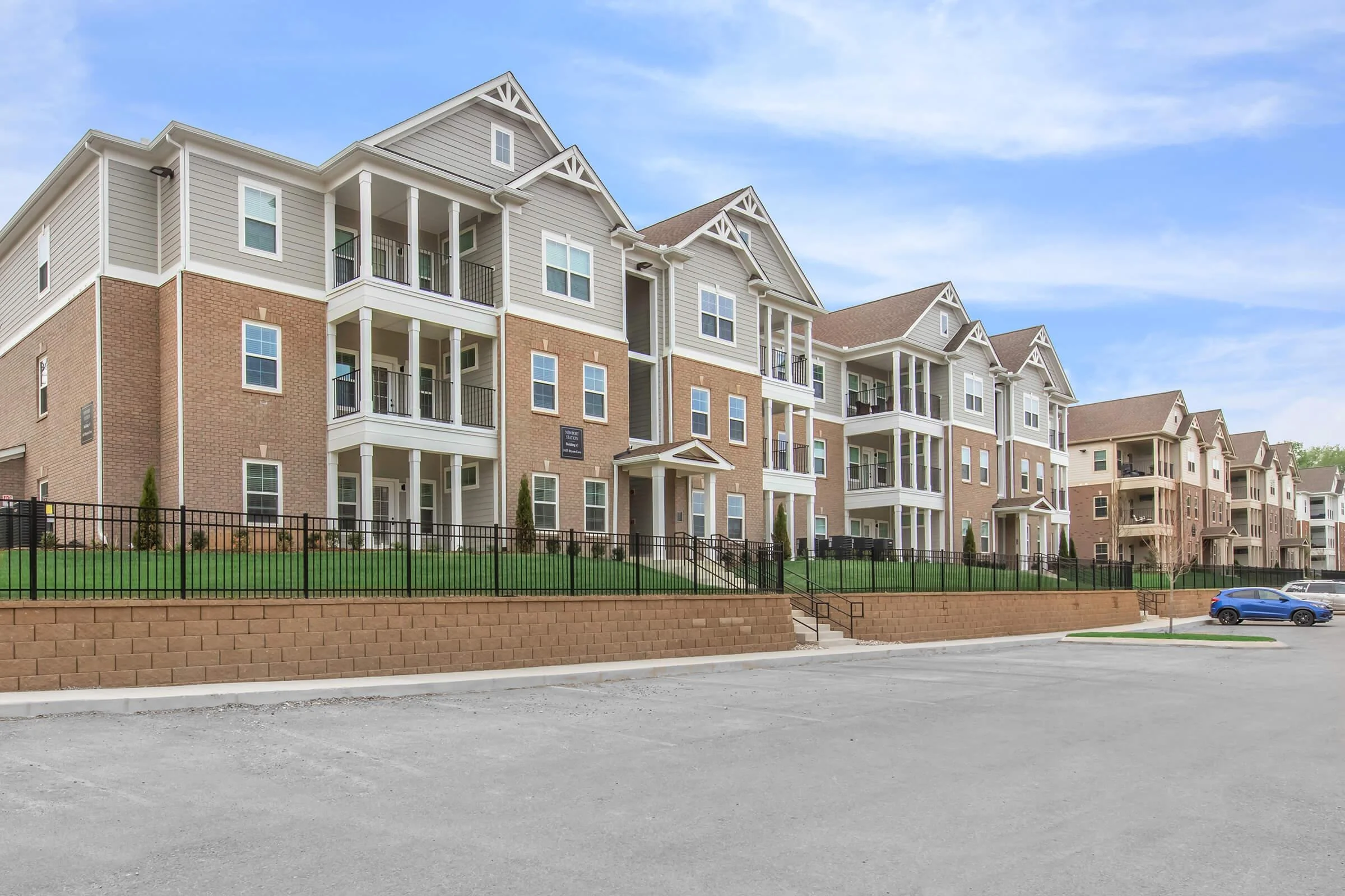 Modern Apartment Complex View of a row of modern apartment buildings with brick exteriors and balconies, set against a clear blue sky.