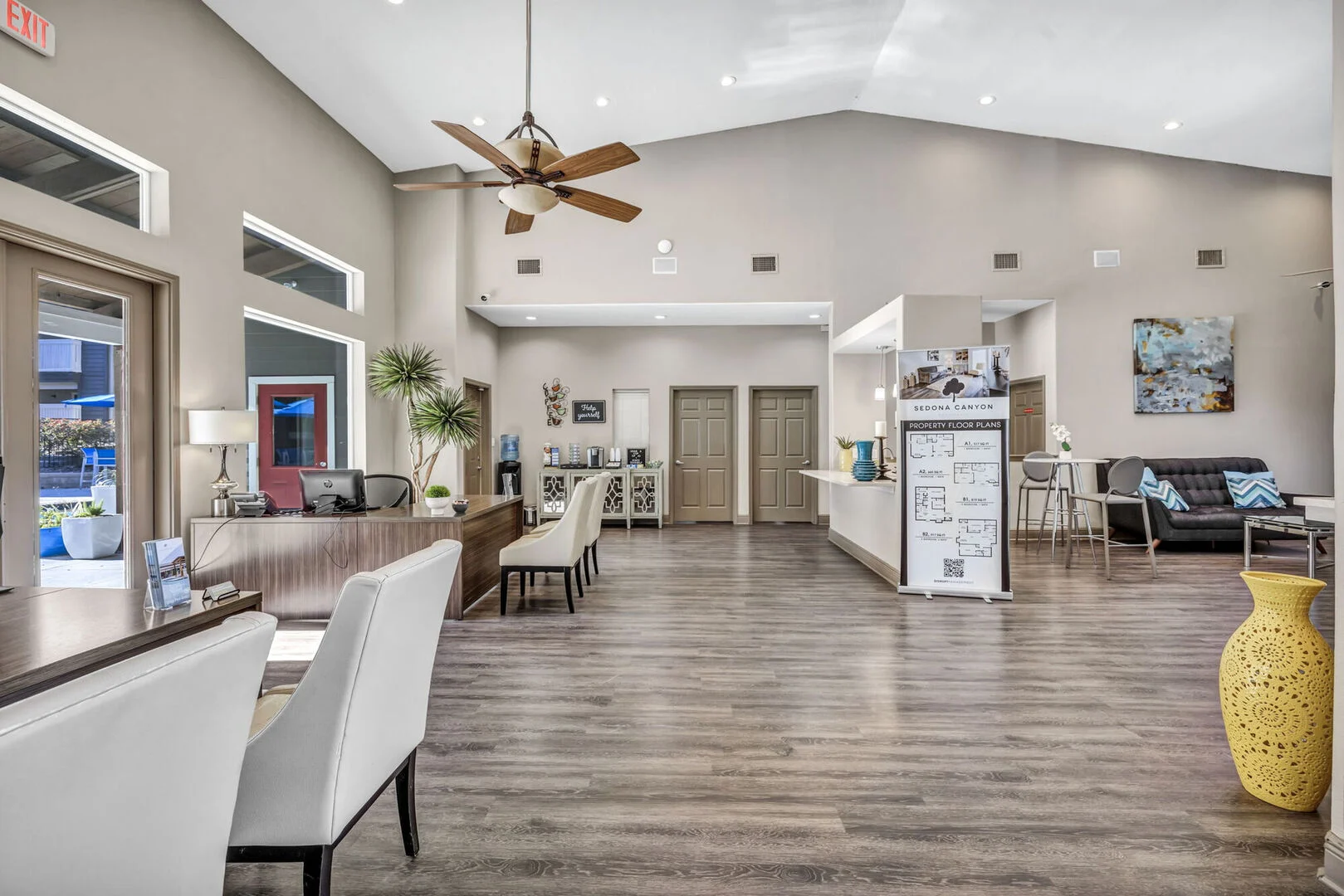 A spacious and modern lobby with a seating area, reception desk, and decorative elements including plants and artwork.