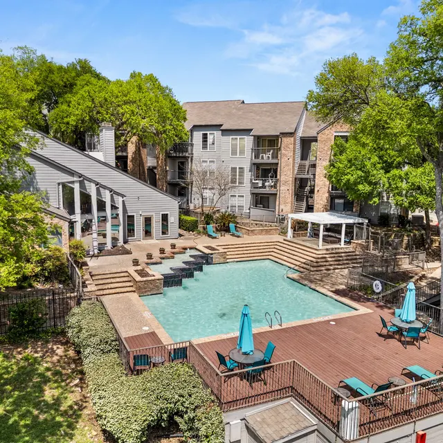 Aerial view of a swimming pool area surrounded by apartments and greenery.