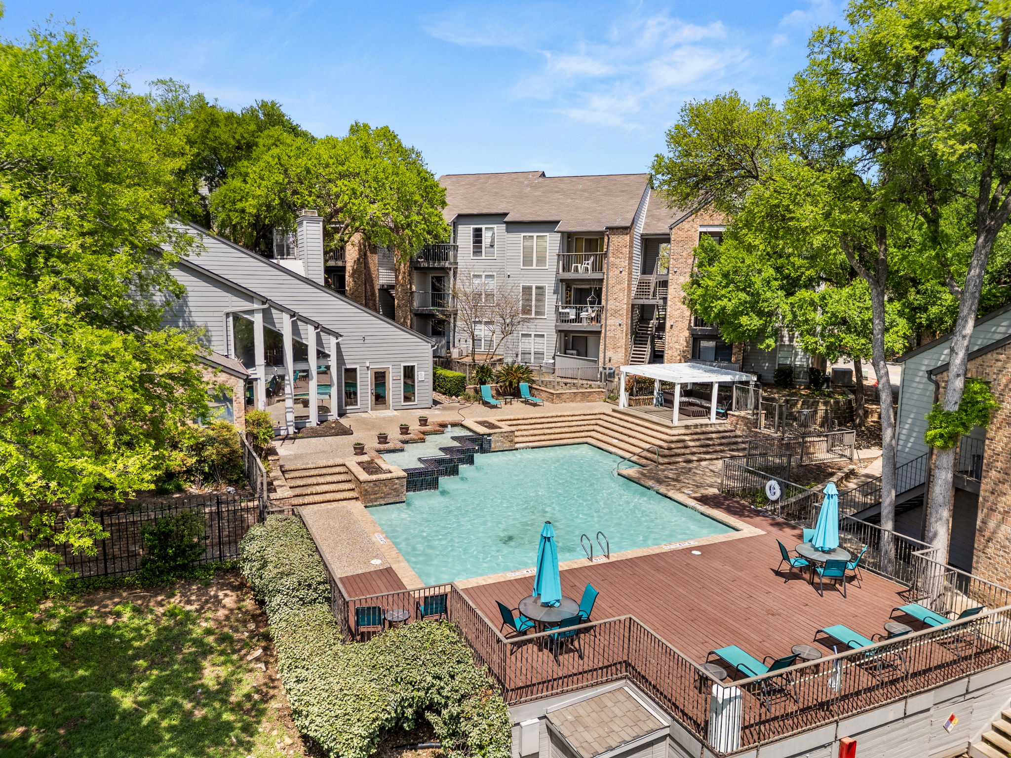 Aerial view of a swimming pool area surrounded by apartments and greenery.