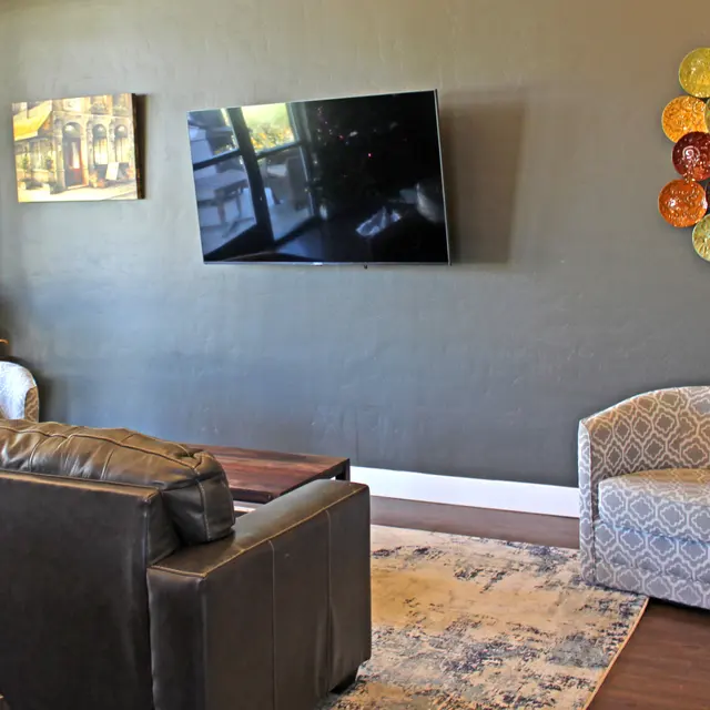 Stylish Living Room Interior Cozy living room featuring a dark green wall, comfortable seating, a large TV mounted on the wall, and decorative wall art.