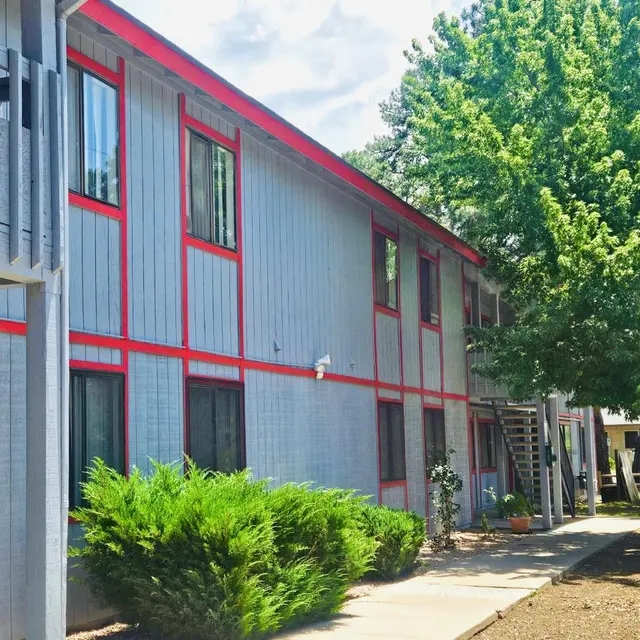 Apartment Complex Exterior Exterior view of an apartment building with red accents and greenery in the foreground.