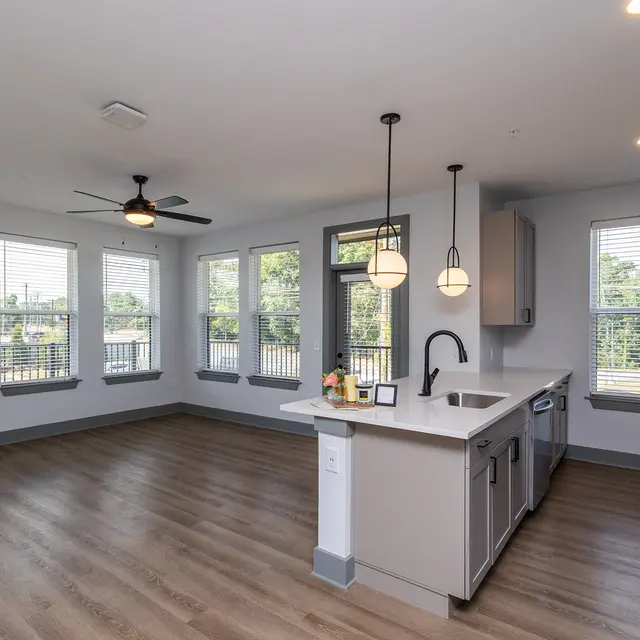 Modern Kitchen and Living Area A modern kitchen and living area with large windows, pendant lights, and wooden flooring