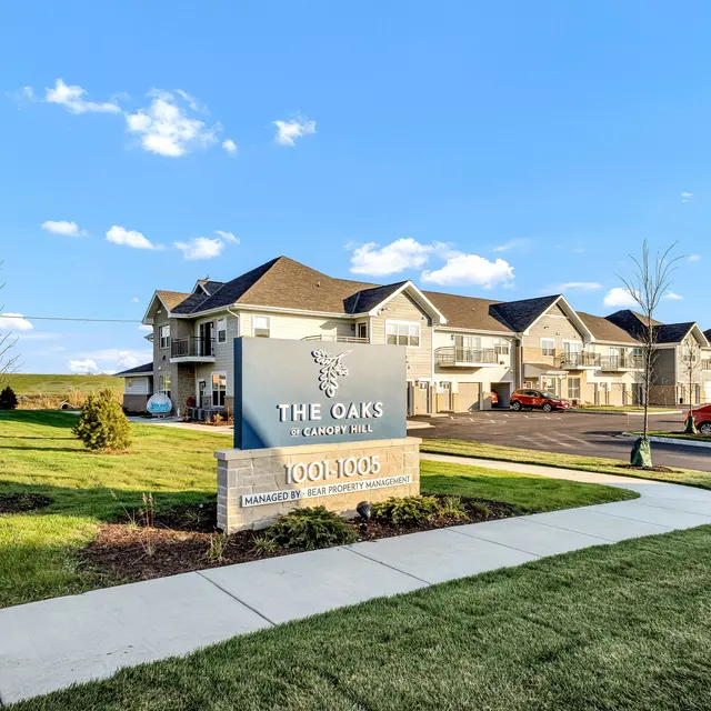 The Oaks at Canyon Hill apartment complex with a sign in front and landscaped area