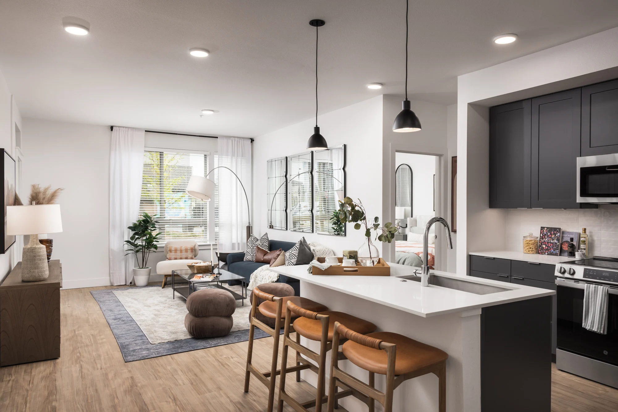 Stylish Modern Apartment Living A modern living space featuring a kitchen and lounge area with stylish furniture, plants, and large windows.