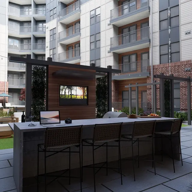 A modern apartment courtyard featuring a bar area with stools, greenery, and seating areas.