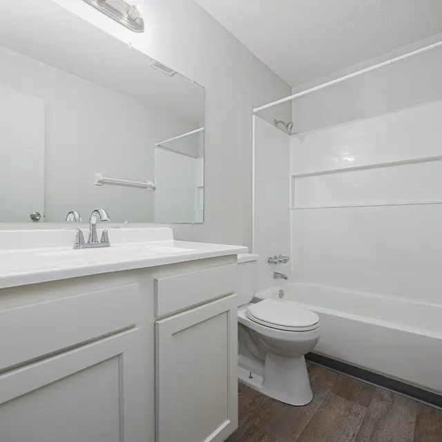 A clean, modern bathroom featuring a white vanity with two sinks, a bathtub with a shower curtain, and light-colored walls.