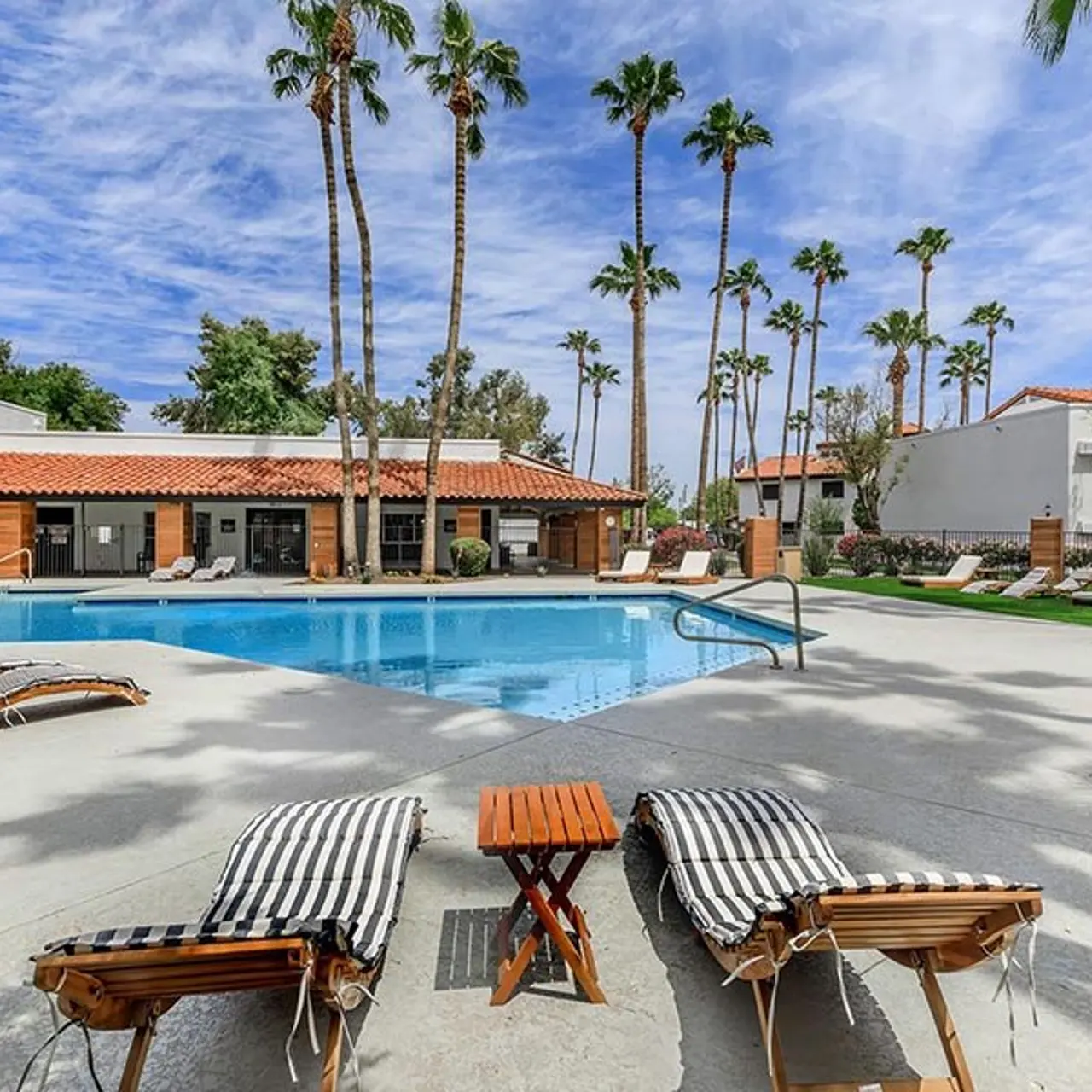 Swimming pool area with lounge chairs and palm trees