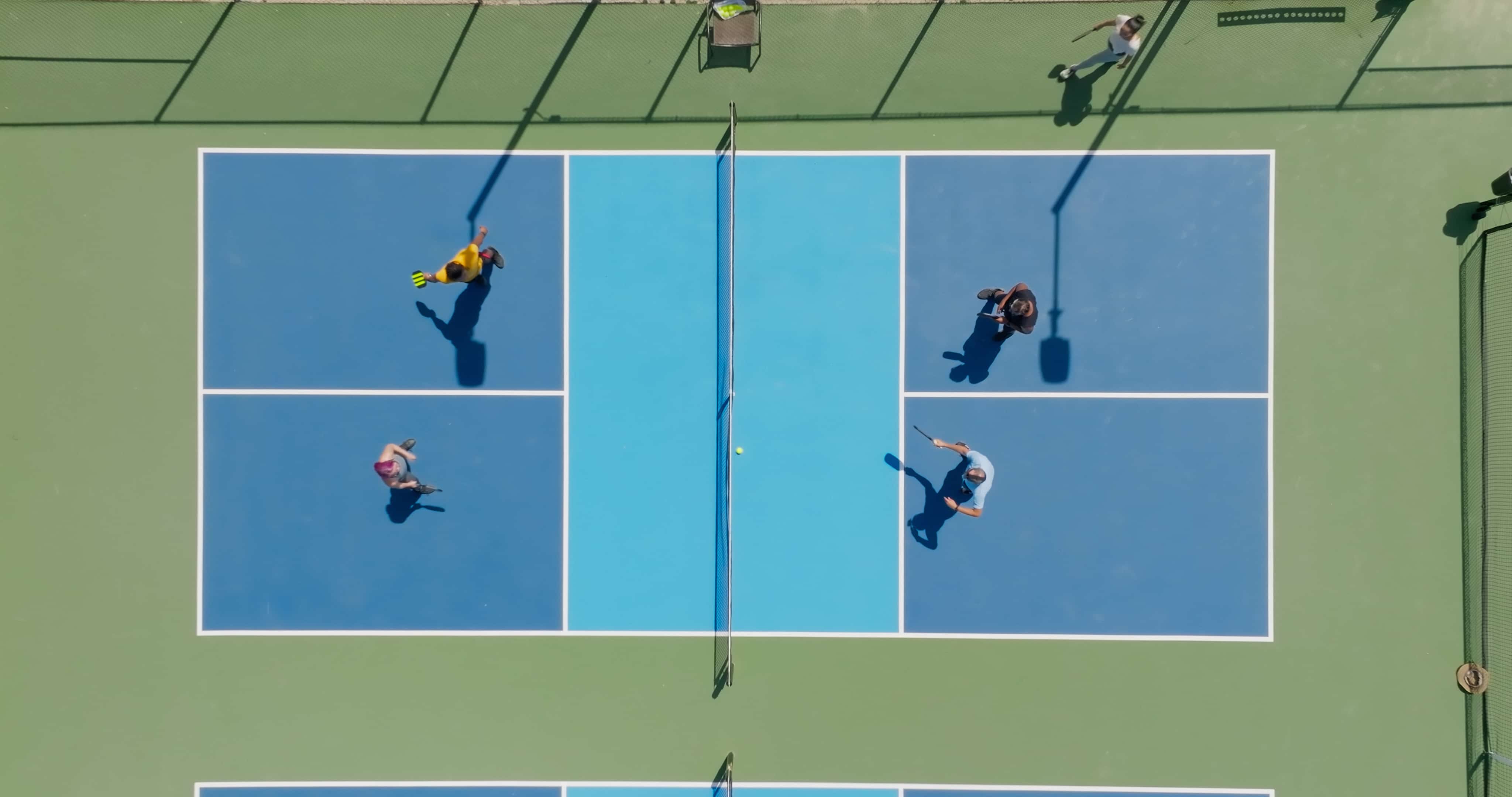 Overhead Tennis Match View An overhead view of a tennis court showing four players engaging in a match.