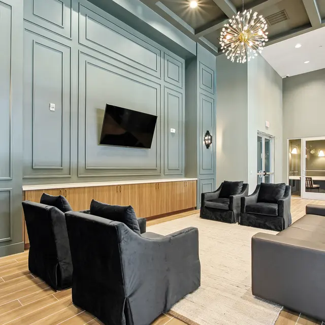 Modern lounge area featuring sleek furniture, a large wall-mounted TV, and elegant wall design with decorative lighting.