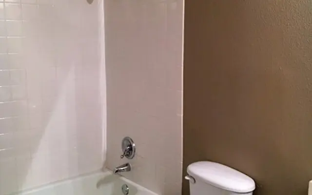 Minimalist Bathroom Interior A simple bathroom featuring a shower and bathtub combination, a toilet, and a small counter area with a sink.