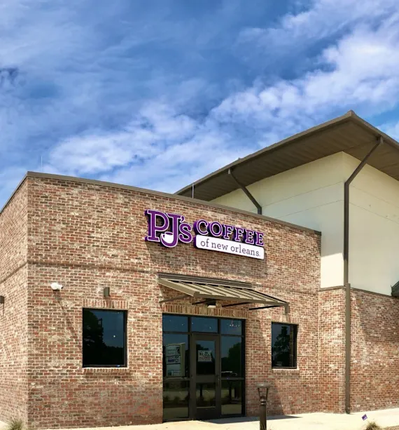 Exterior view of PJ's Coffee of New Orleans building with a clear blue sky.