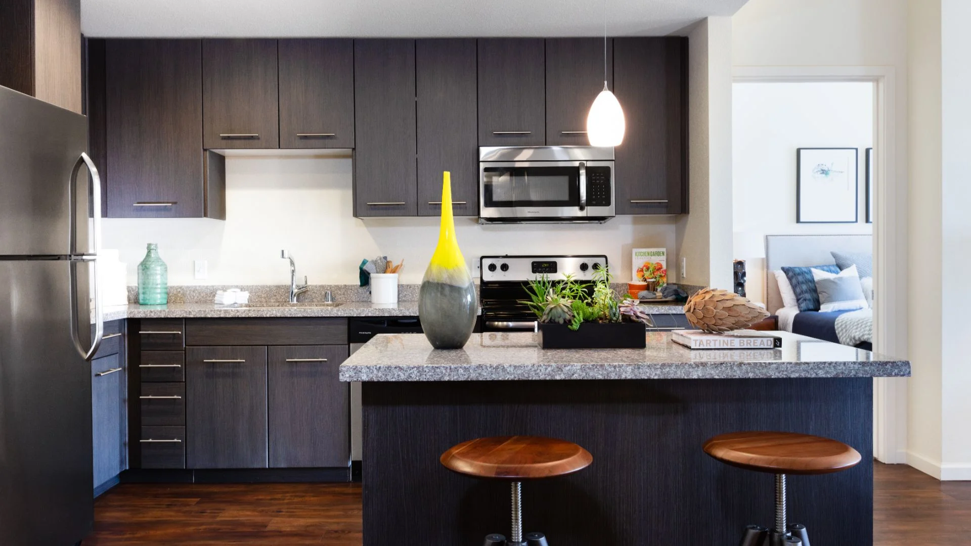 Stylish Modern Kitchen A modern kitchen featuring dark cabinetry, stainless steel appliances, and a stylish kitchen island with two stools.
