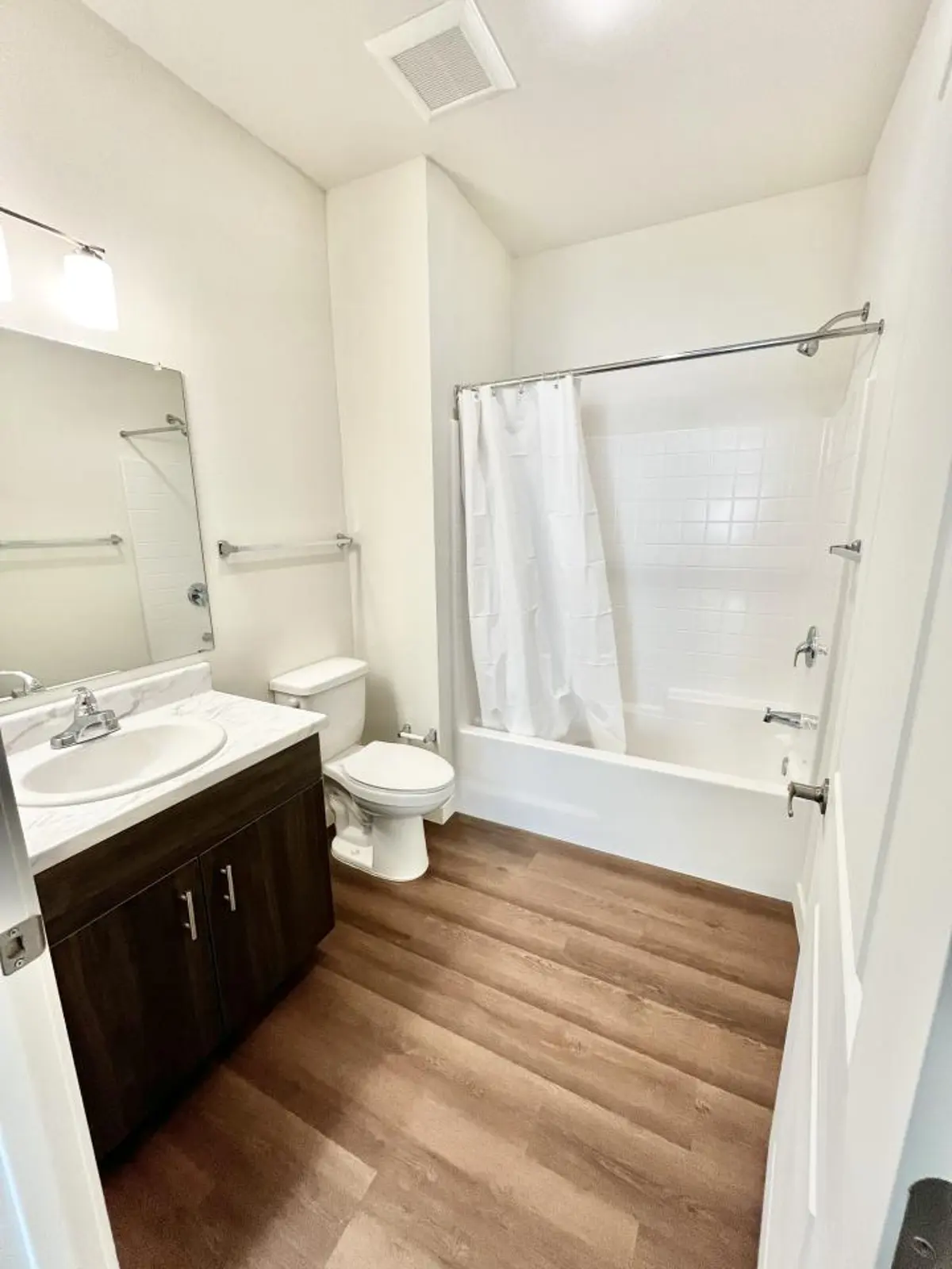Bathroom with vanity, toilet and bathtub behind a shower curtain.