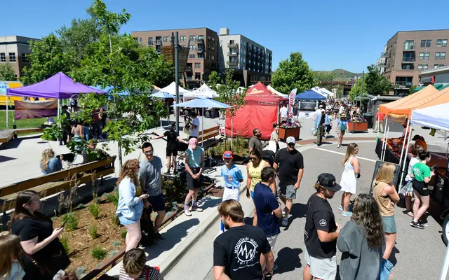 A vibrant outdoor market scene with colorful tents and a crowd of people enjoying the event.