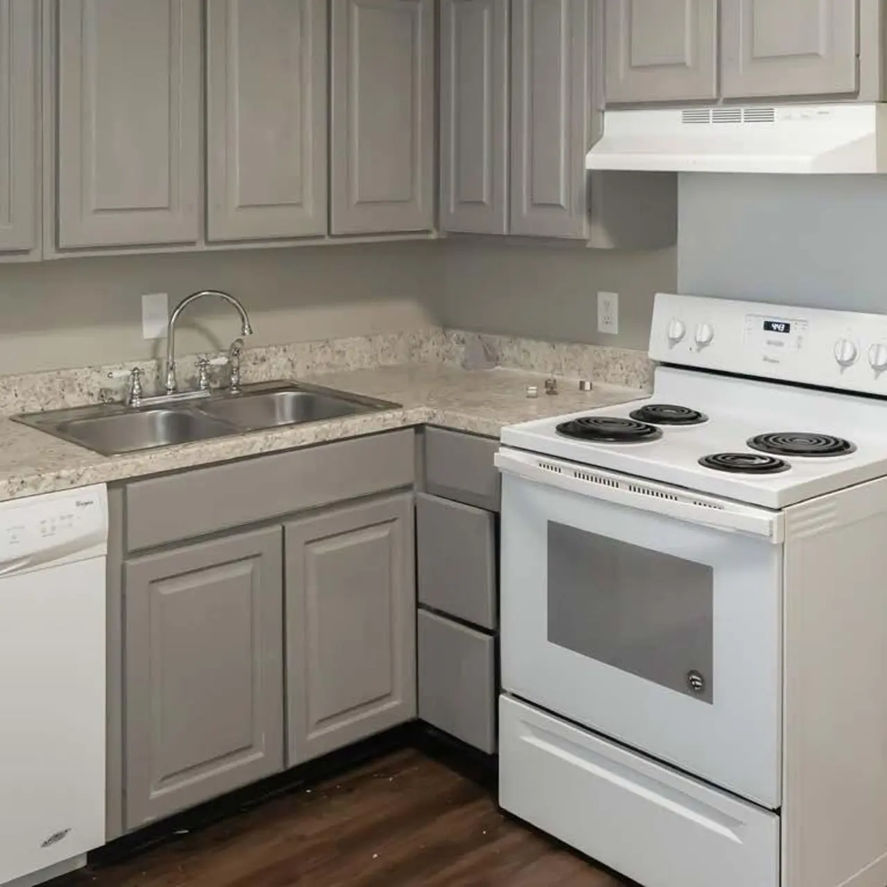 A modern kitchen featuring gray cabinets, a double sink, a white stove with four burners, and a dishwasher.