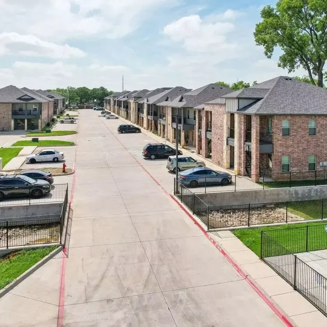 Aerial view of a residential apartment complex with parking and grassy areas.