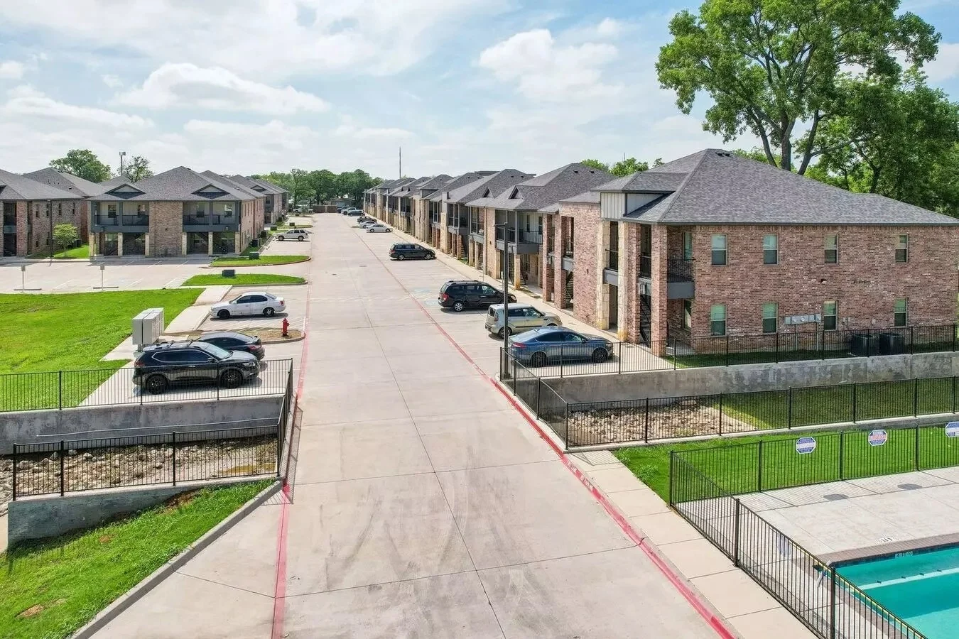 Aerial view of a residential apartment complex with parking and grassy areas.