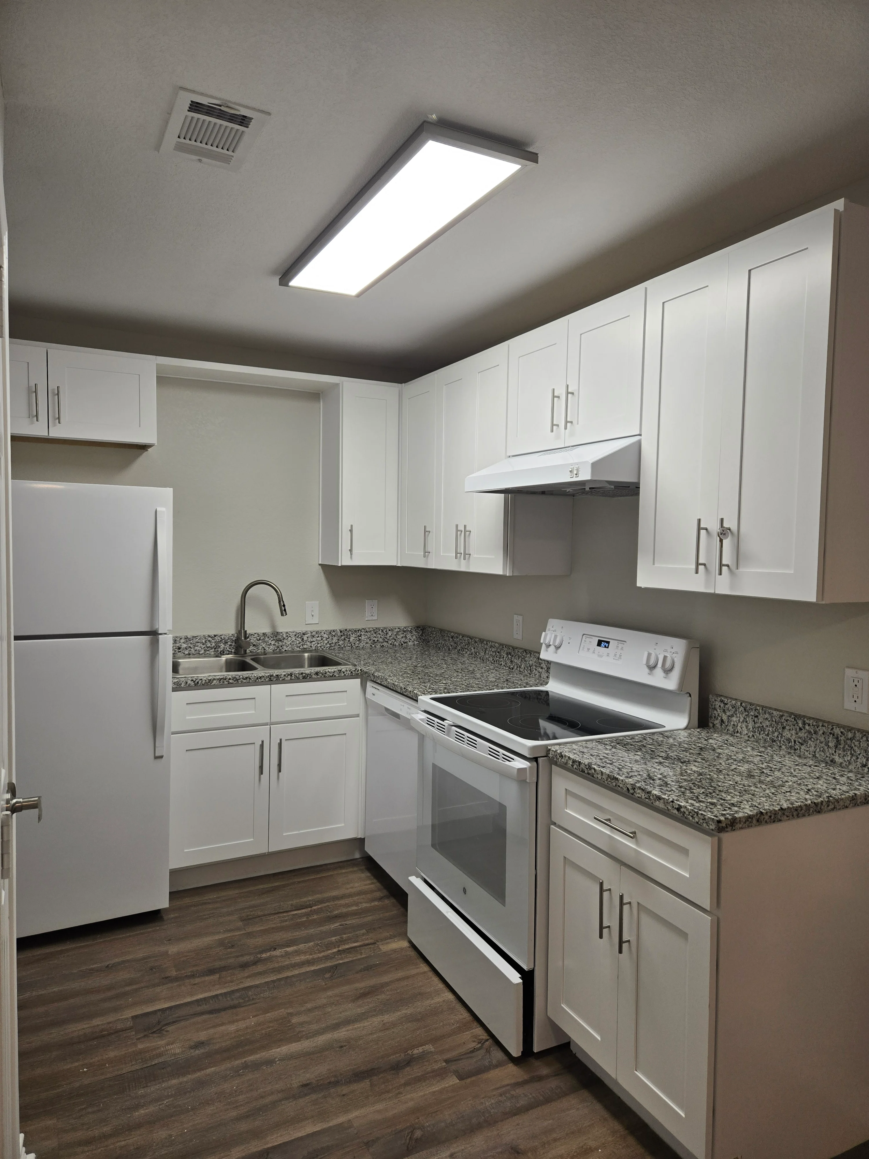 Modern Kitchen Interior A modern kitchen featuring white cabinetry, granite countertops, stainless steel appliances, and wood-like flooring.