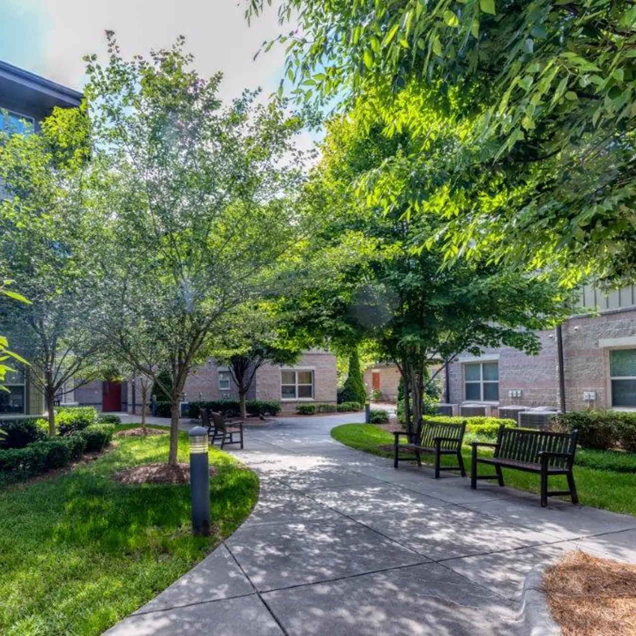A serene courtyard with trees and benches surrounded by buildings.