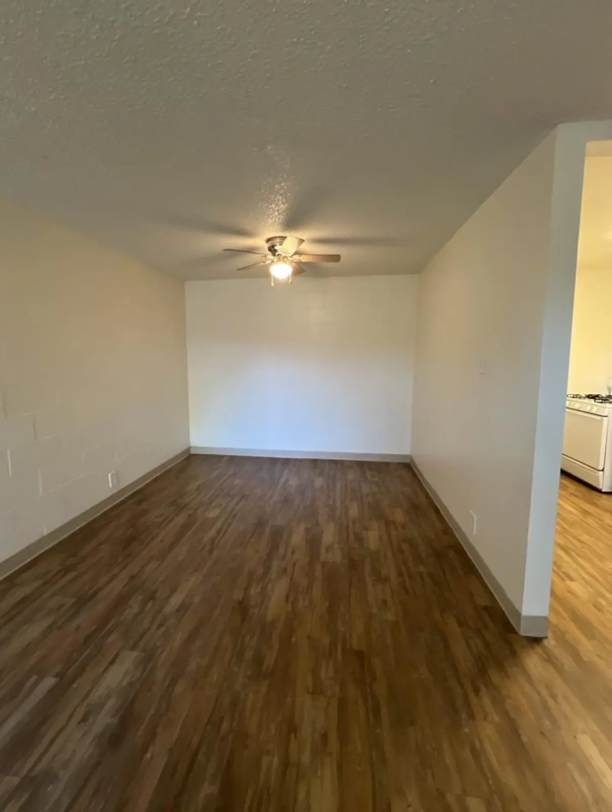 Living room viewed toward a ceiling fan, with the adjoining kitchen at right.
