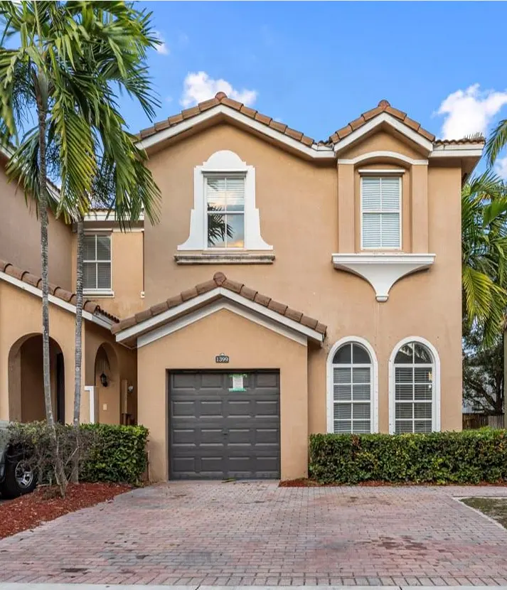 Front view of a two-story home with a garage and palm trees.