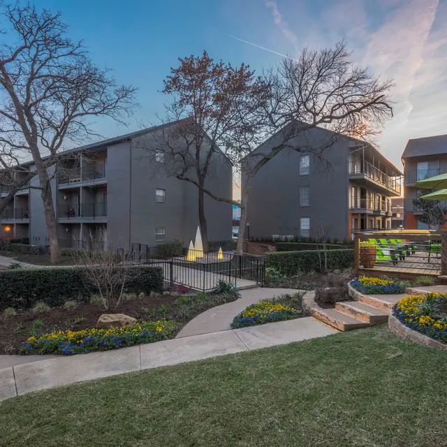 View of an apartment complex with landscaped gardens, walkways, and outdoor seating areas.