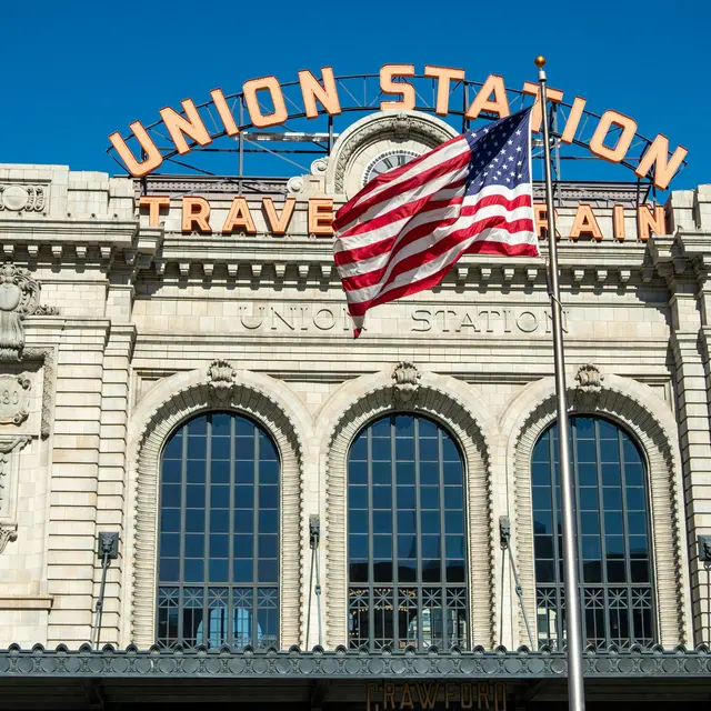 The exterior of Union Station featuring large arched windows, decorative stonework, and an American flag in front.