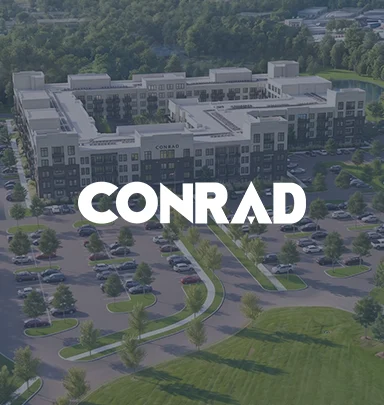 Aerial view of the Conrad apartment complex with surrounding parking and landscaped areas.