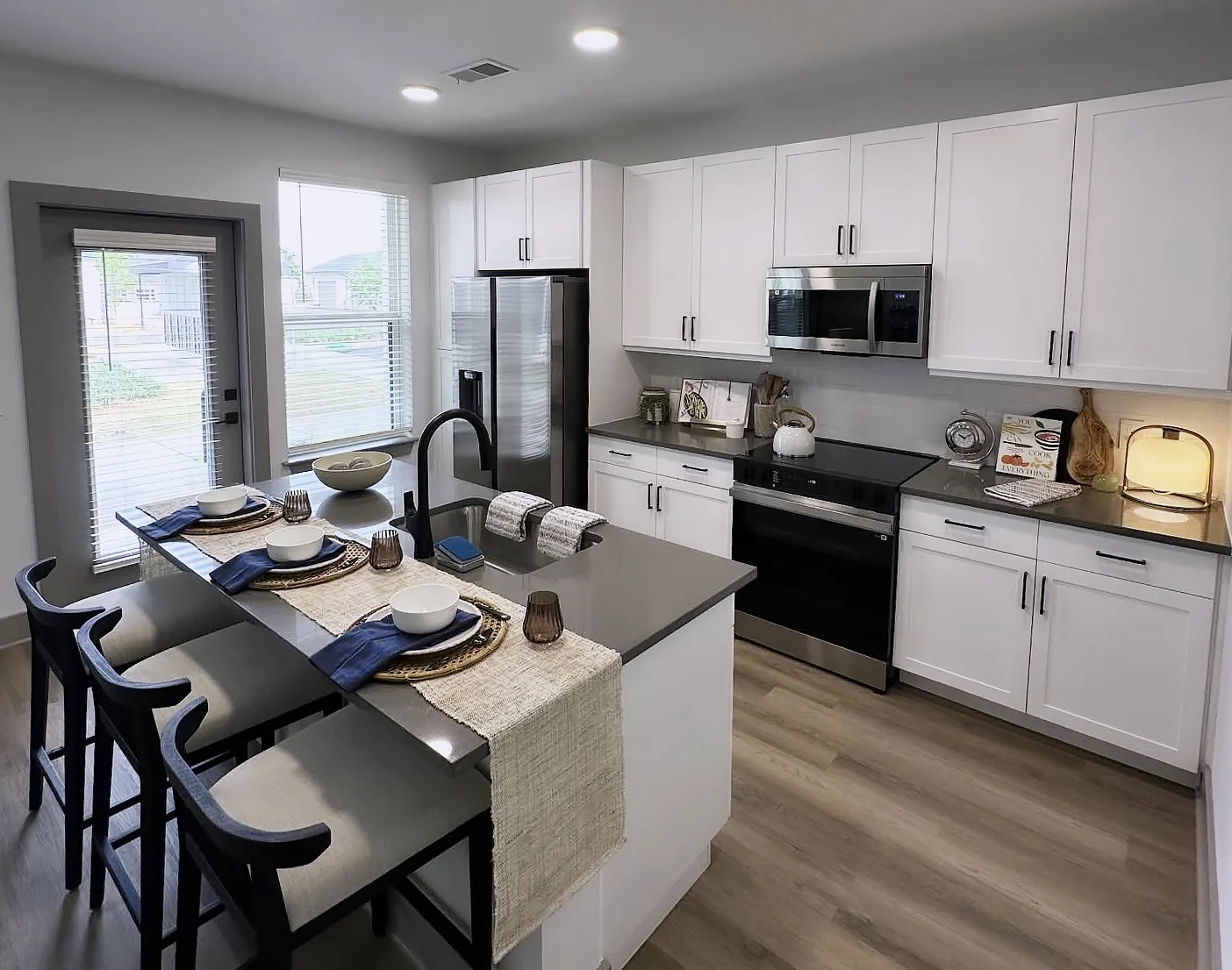Modern Kitchen Design A modern kitchen featuring white cabinetry, a large island with seating, and stainless steel appliances. The space is bright with natural light coming through the window.