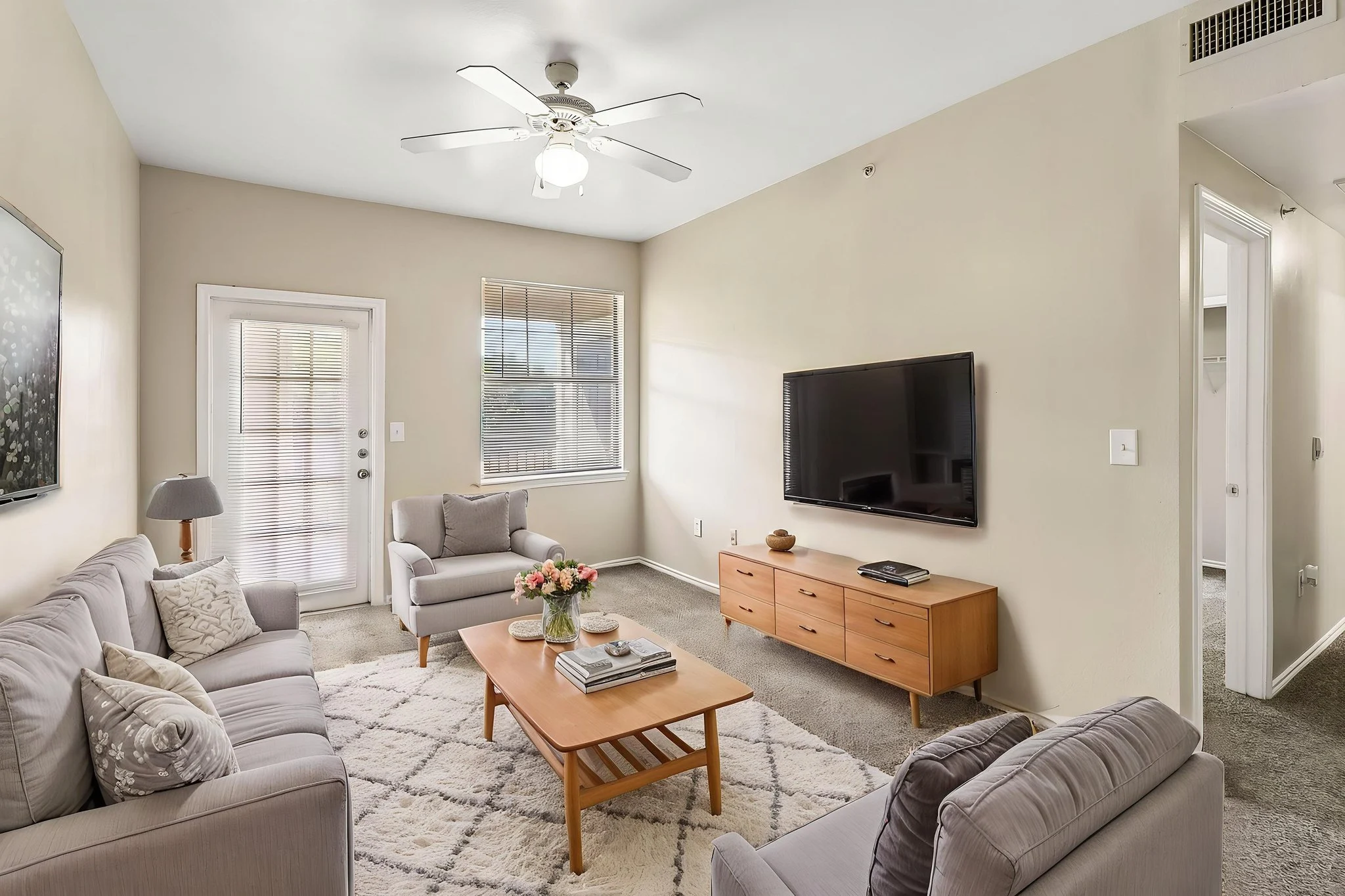 Cozy living room with grey sofas, a wooden coffee table, and a TV on the wall.