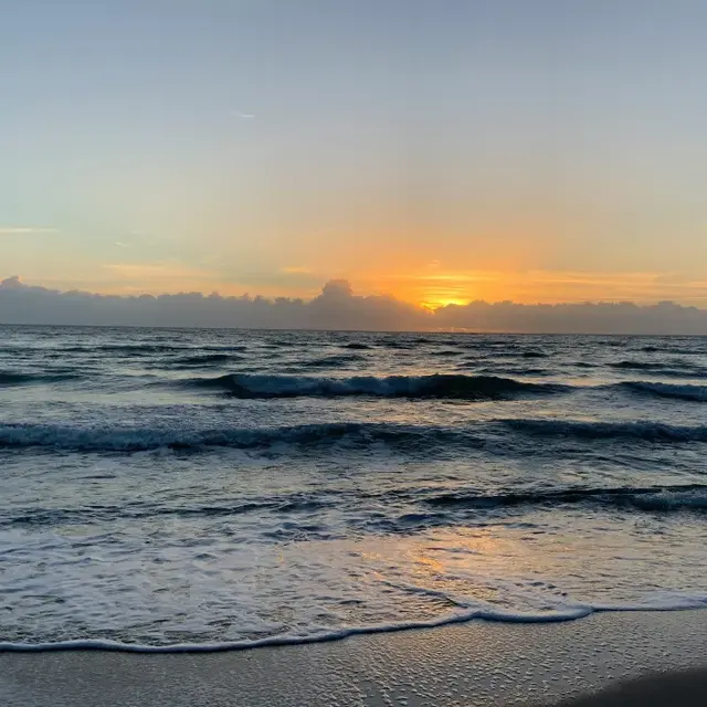 Sunset Over the Ocean A serene view of the ocean during sunset, with vibrant colors in the sky and gentle waves lapping at the shore.