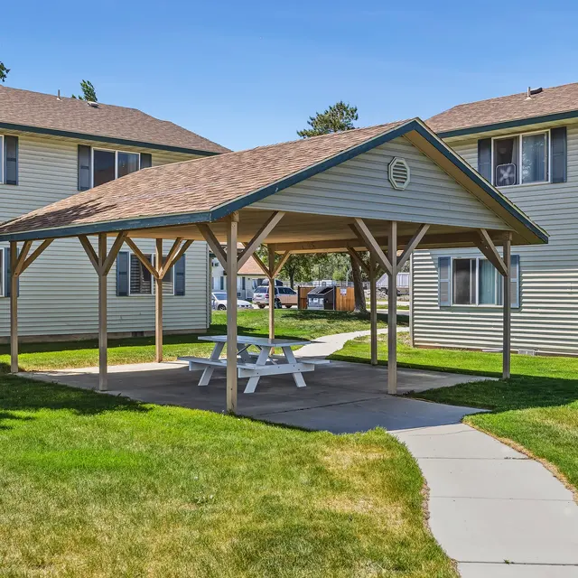 Picnic Area at Apartment Complex A gazebo with picnic tables surrounded by apartment buildings and grass.