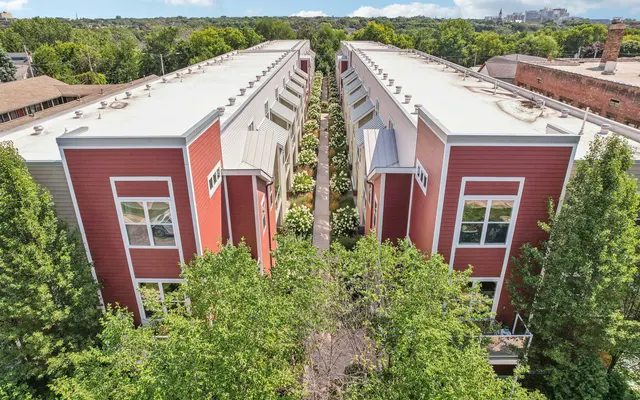 An aerial view of a residential housing complex featuring red buildings with white roofs, surrounded by greenery.