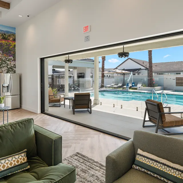 Modern Lounge with Pool View Interior view of a modern lounge area with two chairs facing a large sliding door that reveals a swimming pool area outside.
