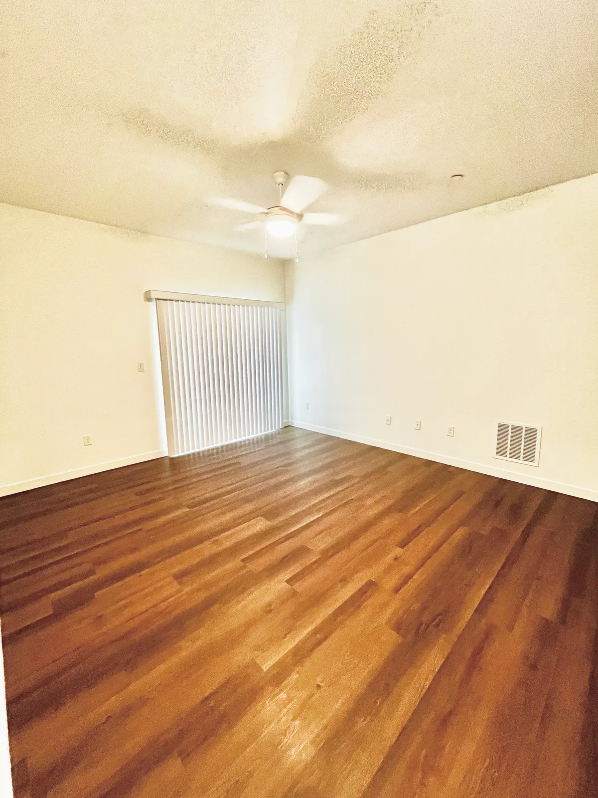 Living area with a ceiling fan and sliding glass door.